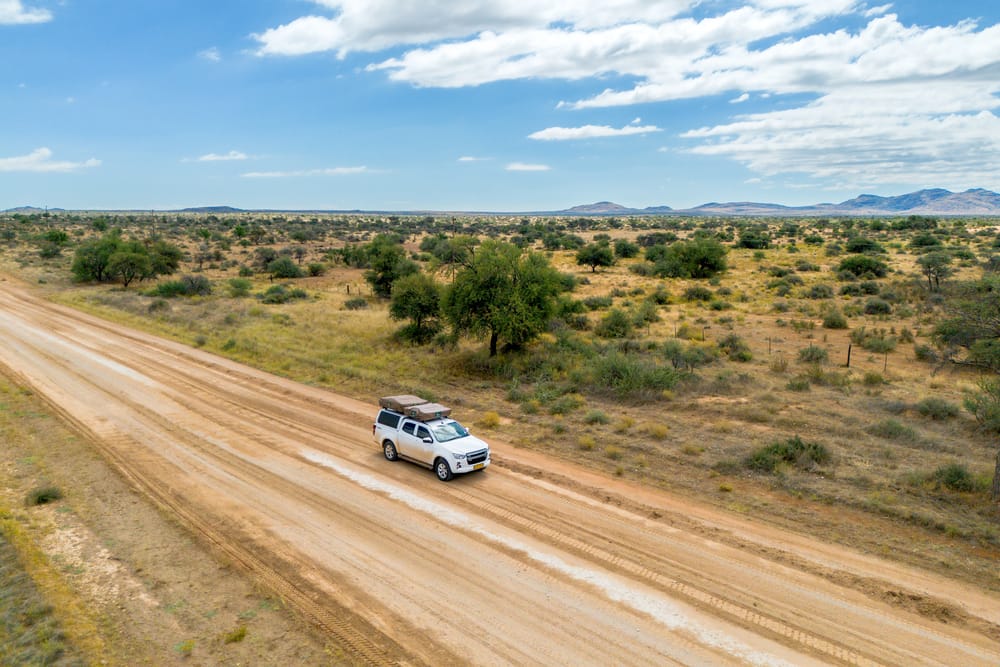 Aerial shot of a 4WD with a hard-shell rooftop tent set up on a remote dirt track in Western Australia