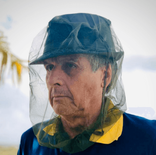 A person wearing a hat with a fly net to protect their face from insects.